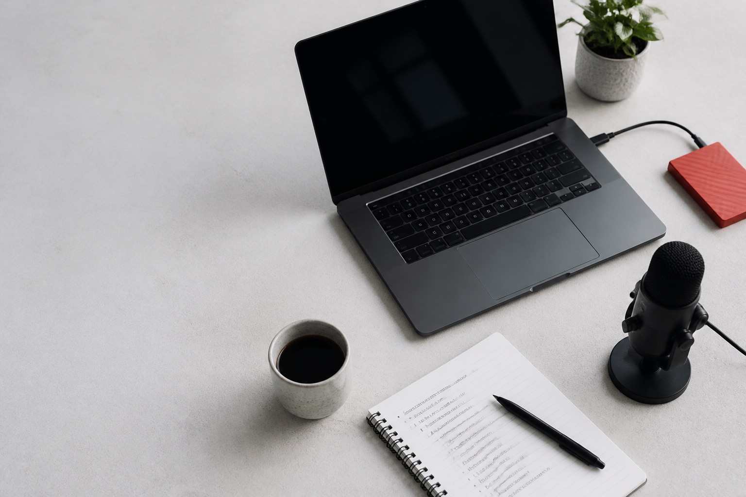 Independent course creator workspace with a laptop, microphone, notebook, and external drive
